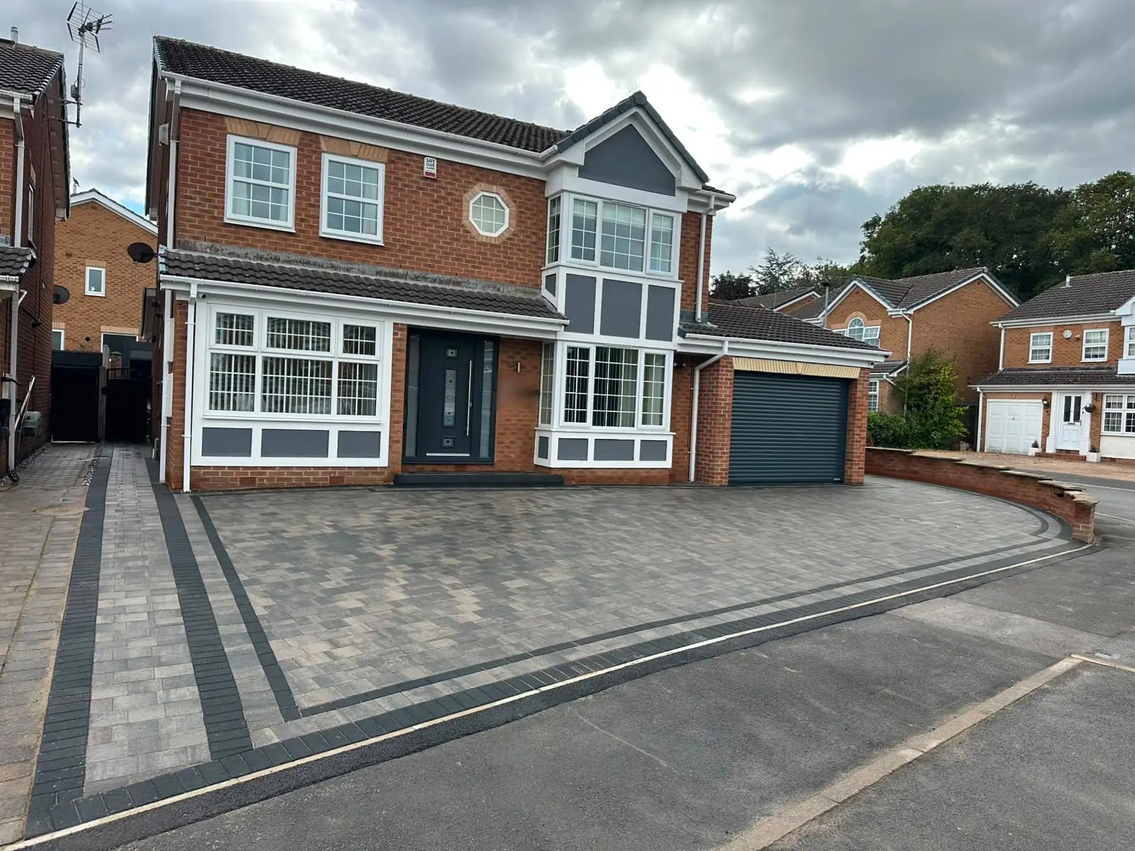 Slate grey block paving with a double charcoal block border across the front of a red-brick detached house in Todwick