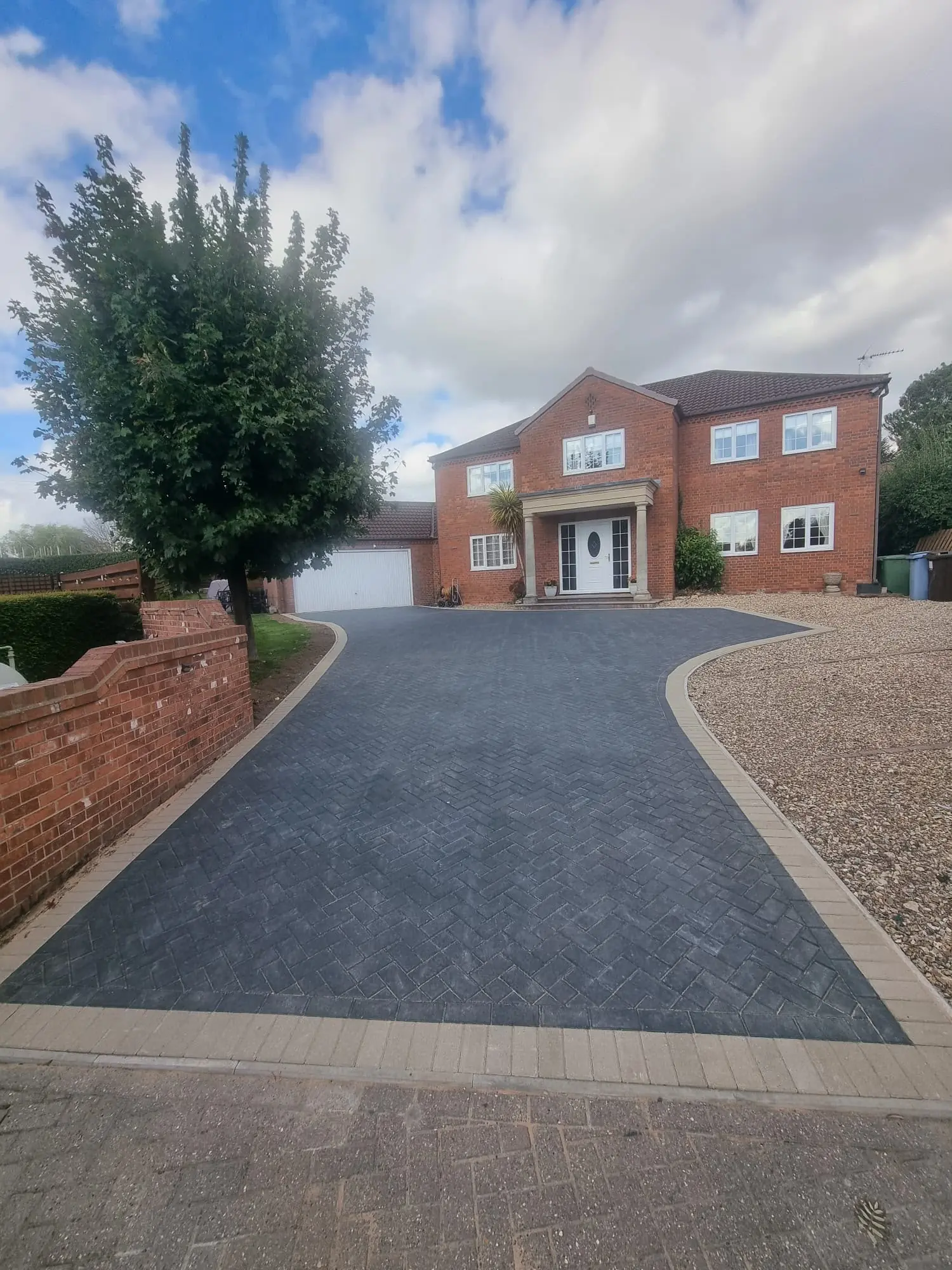 Wide view of the new charcoal block driveway and buff border in front of a Tuxford house