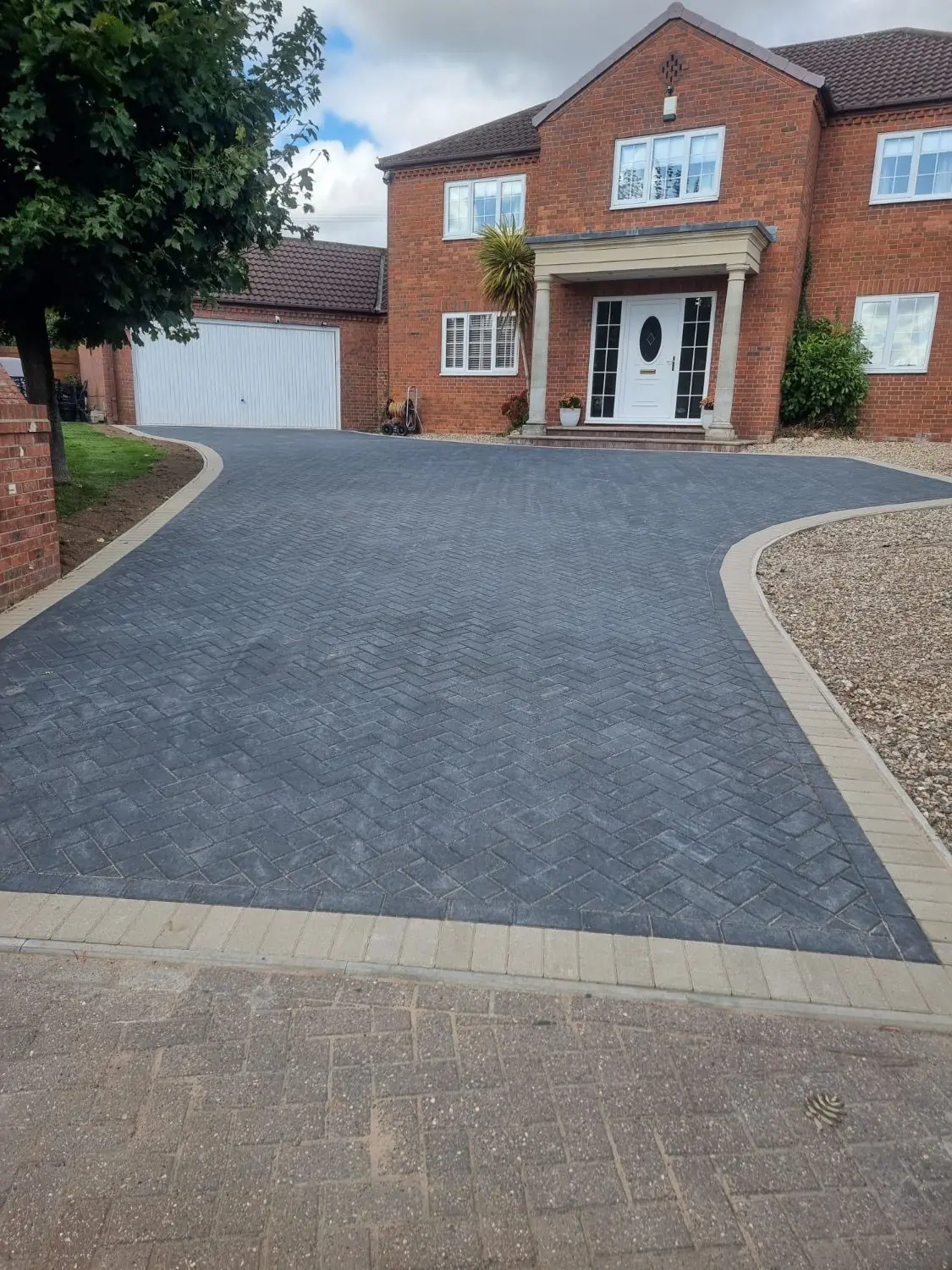 Charcoal block paving with a buff block border in front of a red-brick detached house in Tuxford
