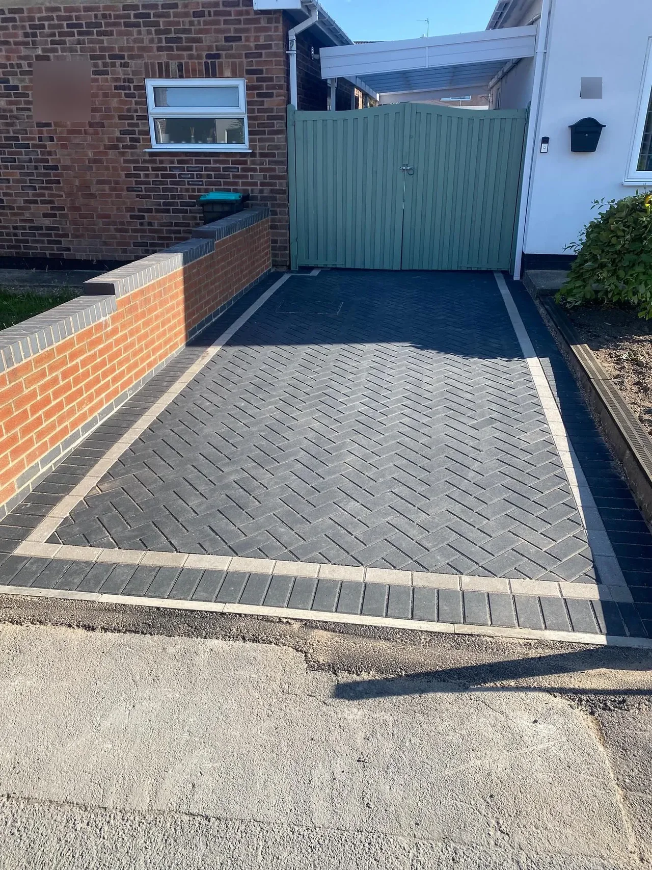 Charcoal block paving with a buff border and a green side gate