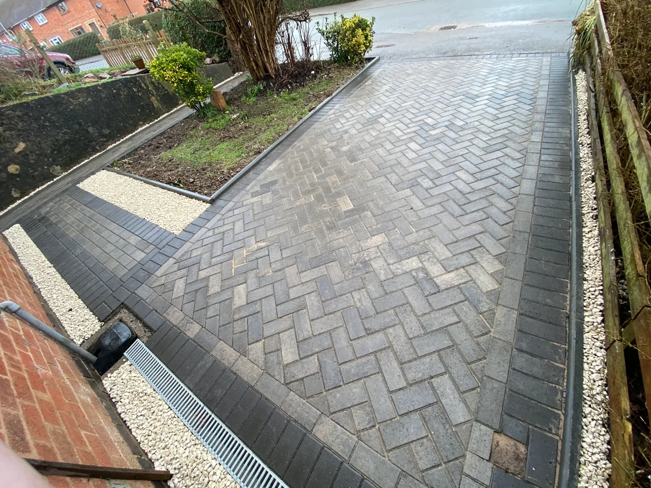 Herringbone block-paved driveway with a charcoal border and drainage channel