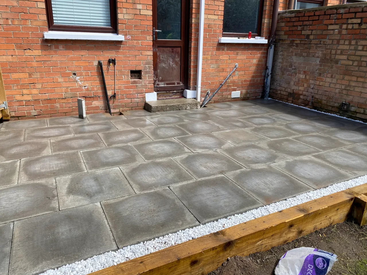 Newly laid patio slabs with a timber edge and stone border