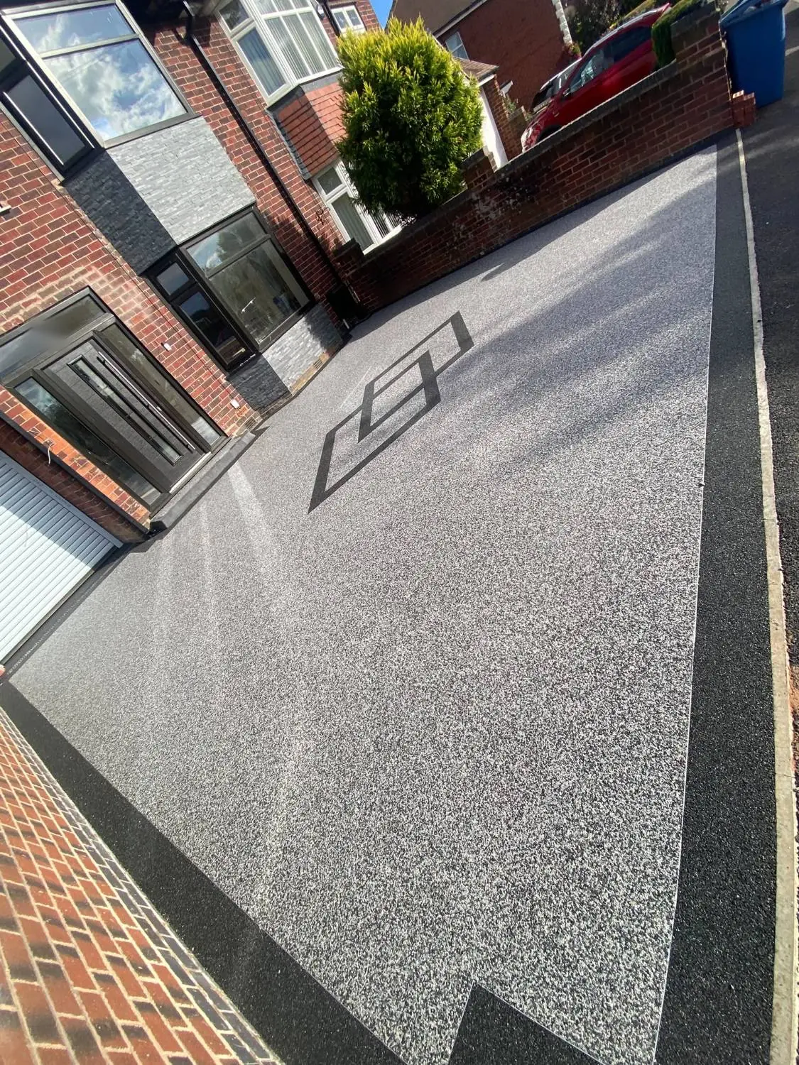 Resin driveway in Mansfield running past the front door, with the black resin border meeting the tarmac crossing
