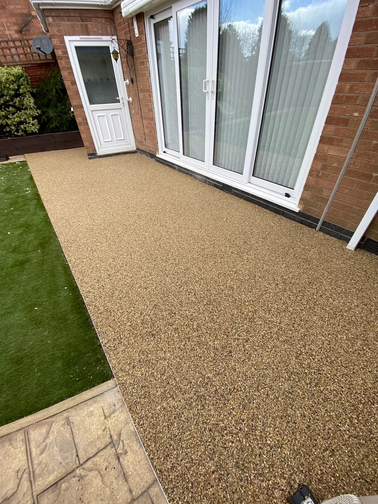 Golden resin-bound path beside a lawn and patio doors