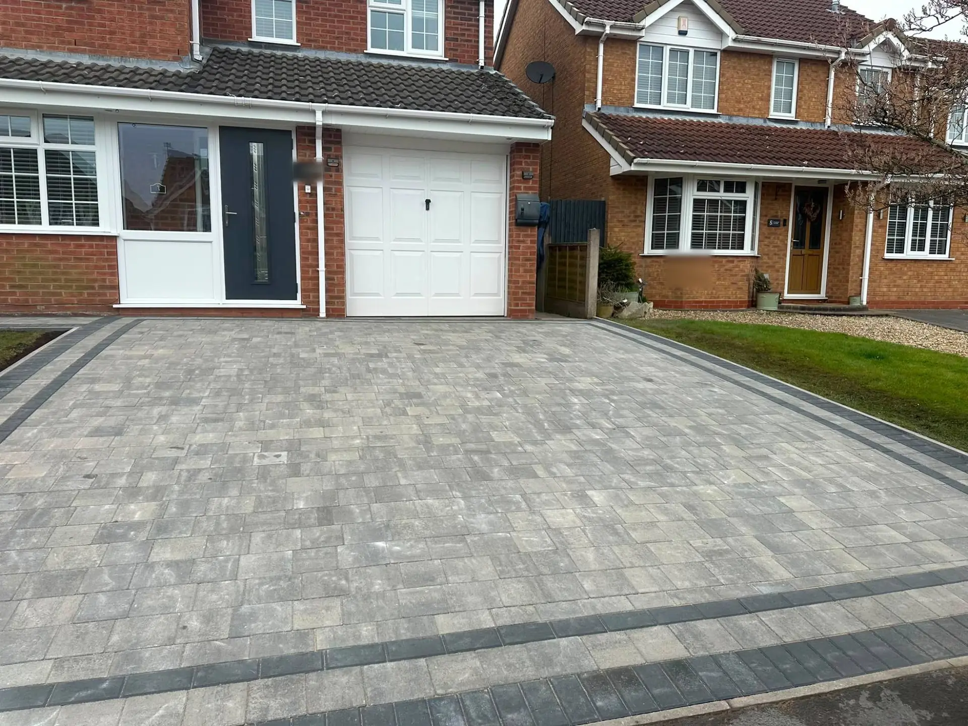 Grey Tegula block paving with a charcoal double border outside a detached house with a garage