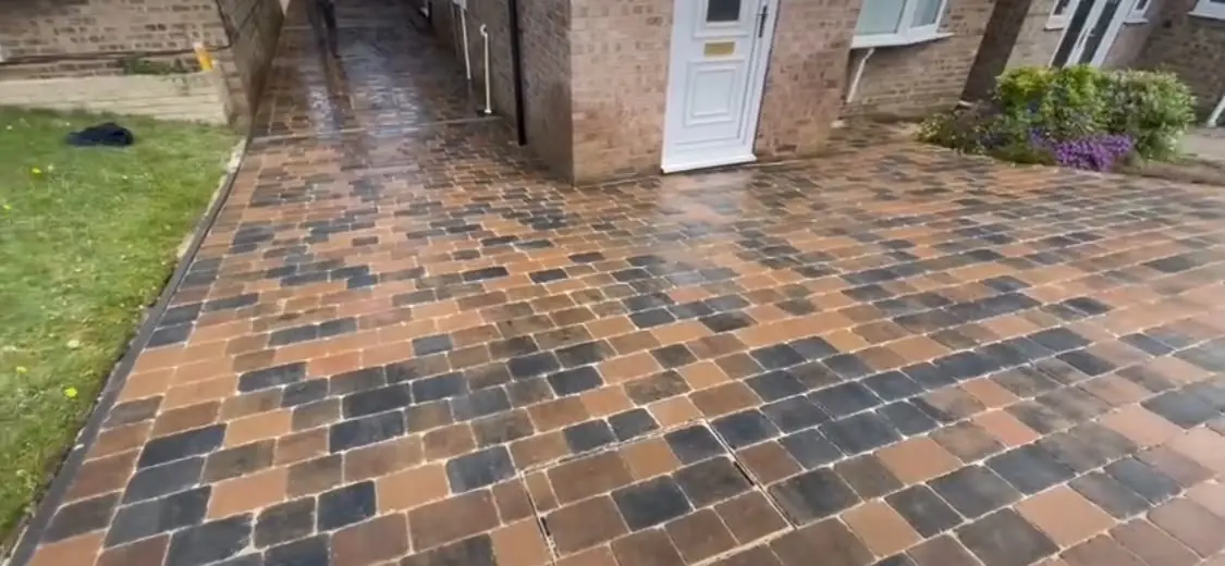 Rustic orange, brown and charcoal Tegula block paving after laying, seen wet at the front of a house