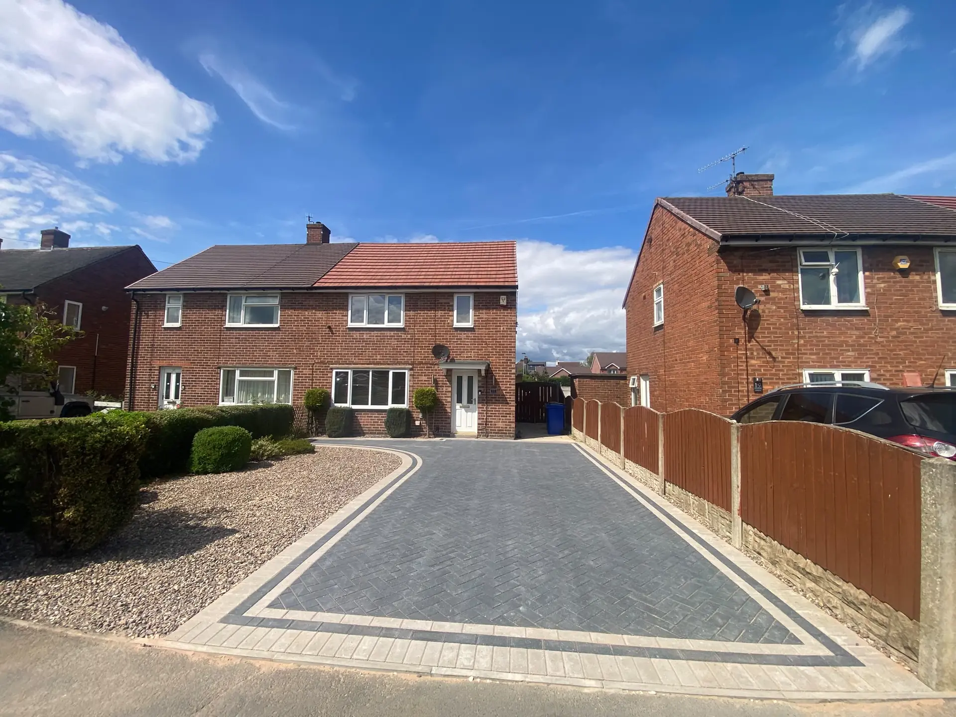 Charcoal herringbone block paving with a double buff border outside a semi-detached house