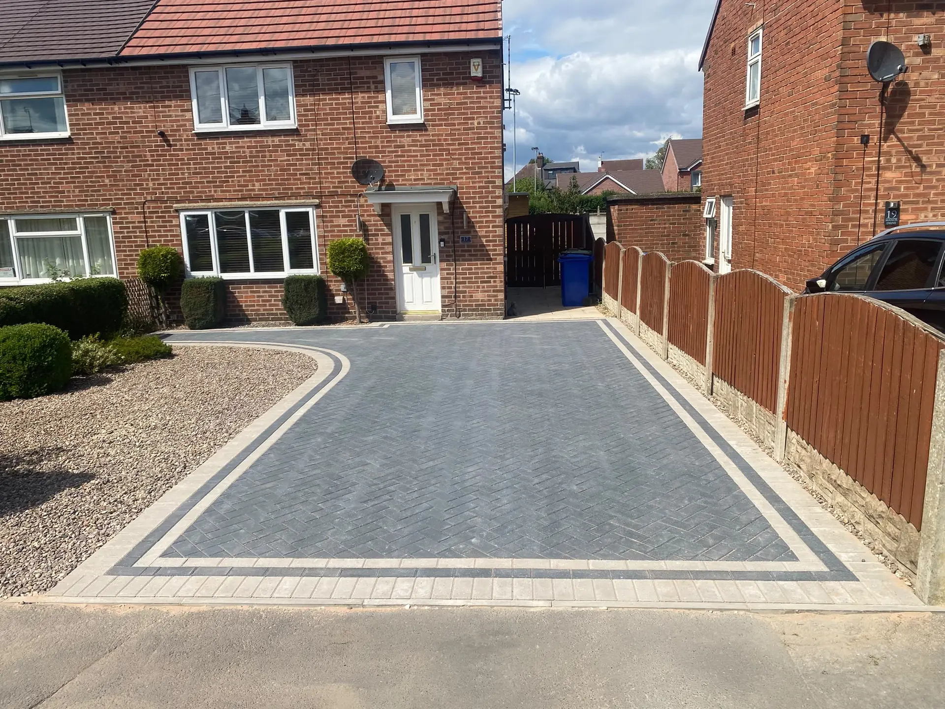 Charcoal block-paved driveway with a buff and charcoal border beside a closeboard fence
