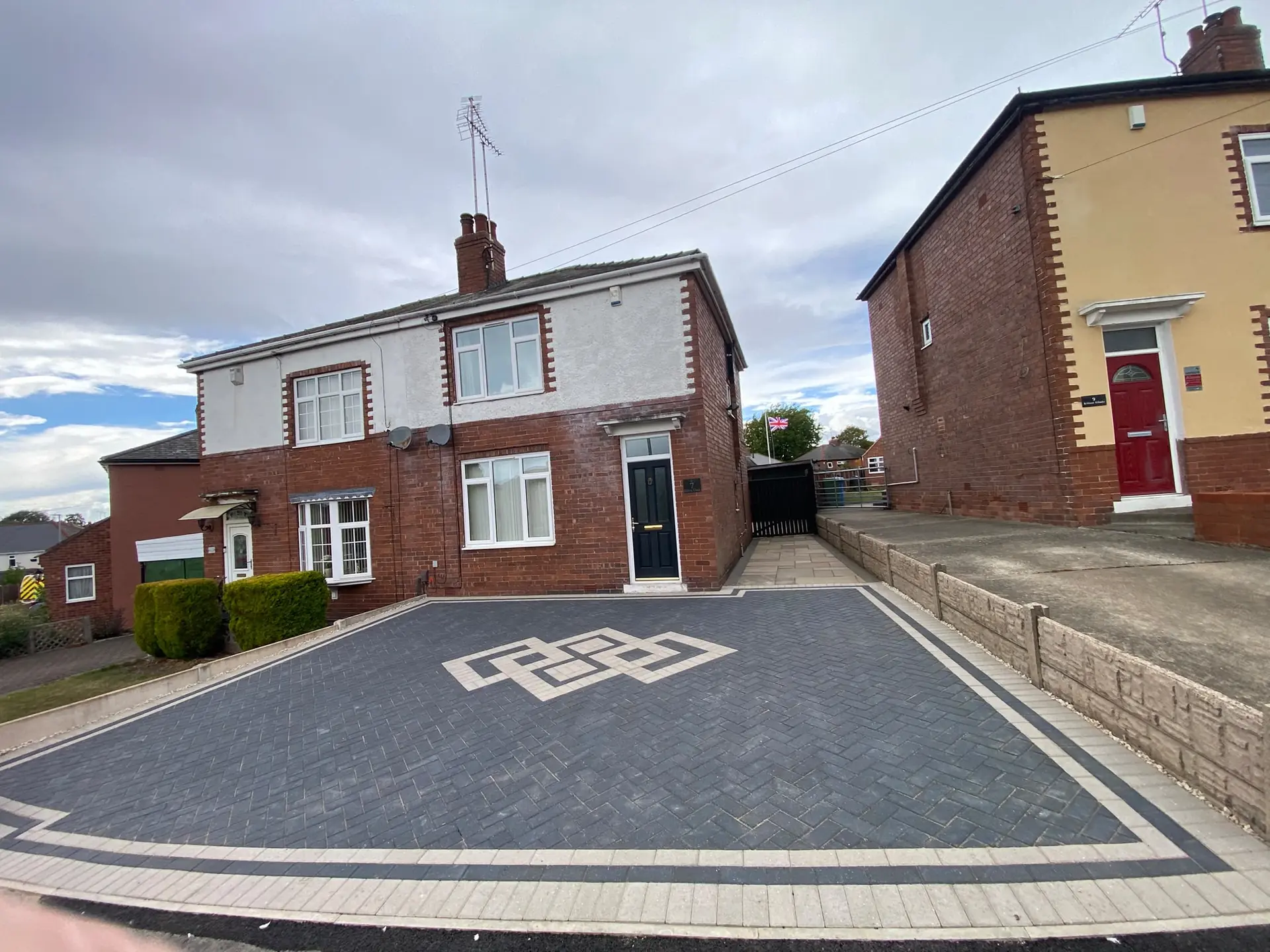 Charcoal block paving with a buff knot inlay in front of a semi-detached house