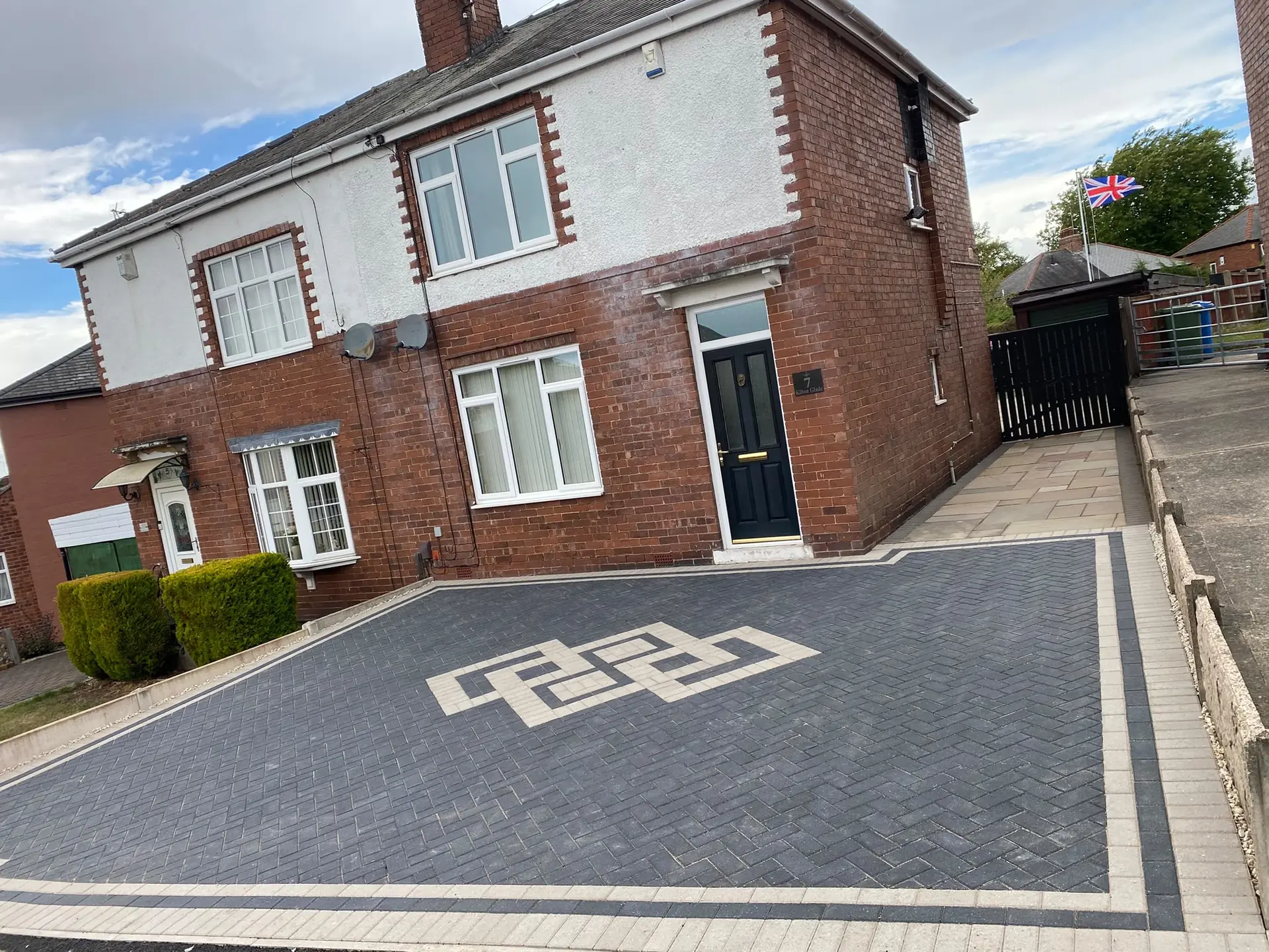 Charcoal herringbone driveway with a buff interlocking knot inlay and buff border