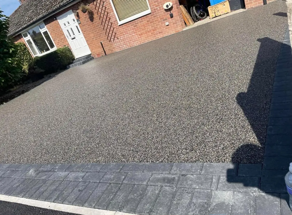 Dark grey resin bound driveway with a block border