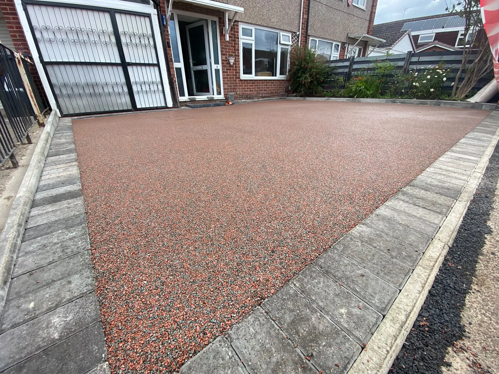 Red resin bound driveway edged with grey block paving