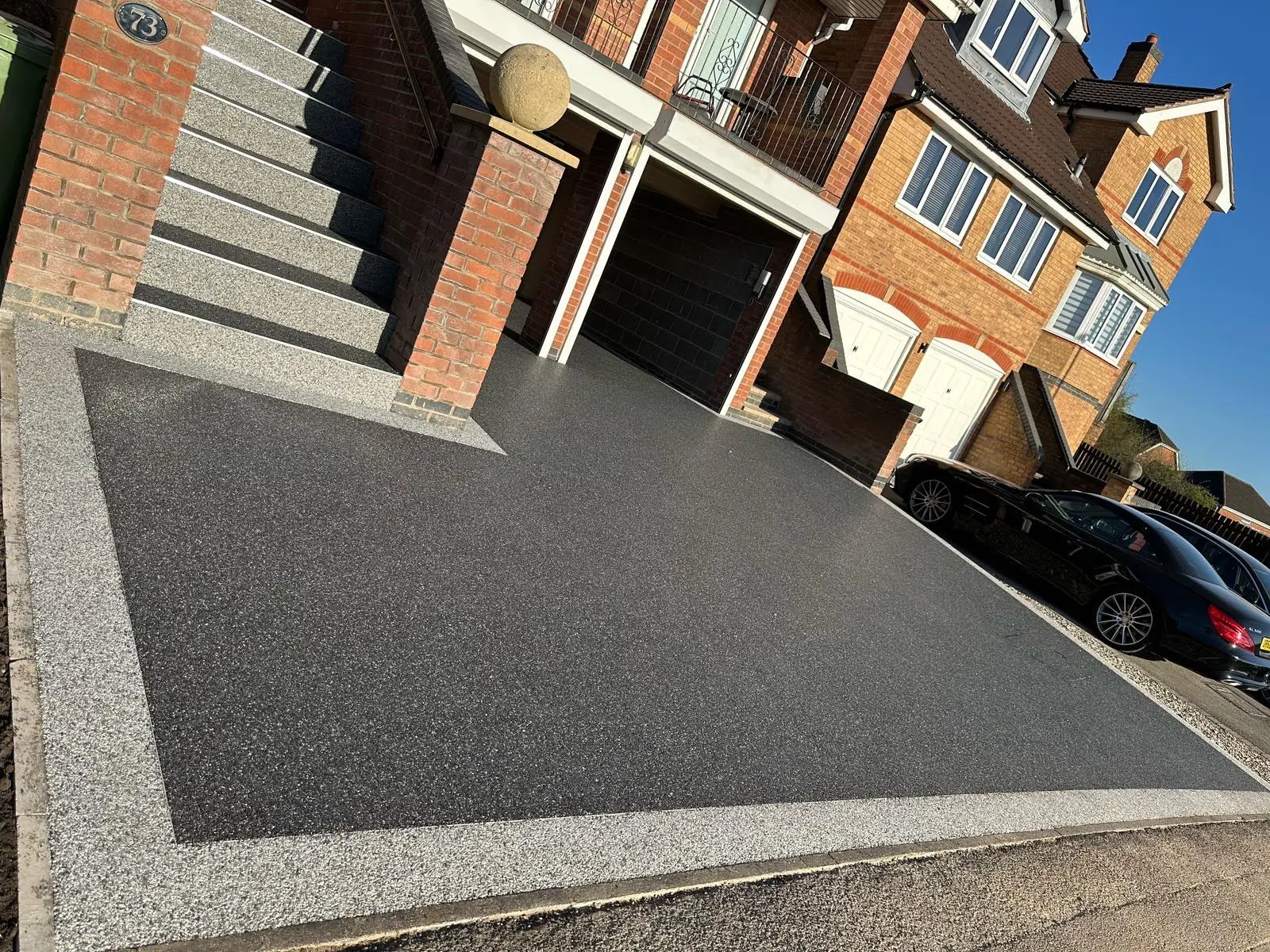 Charcoal resin bound driveway with a light stone border and resin-finished steps