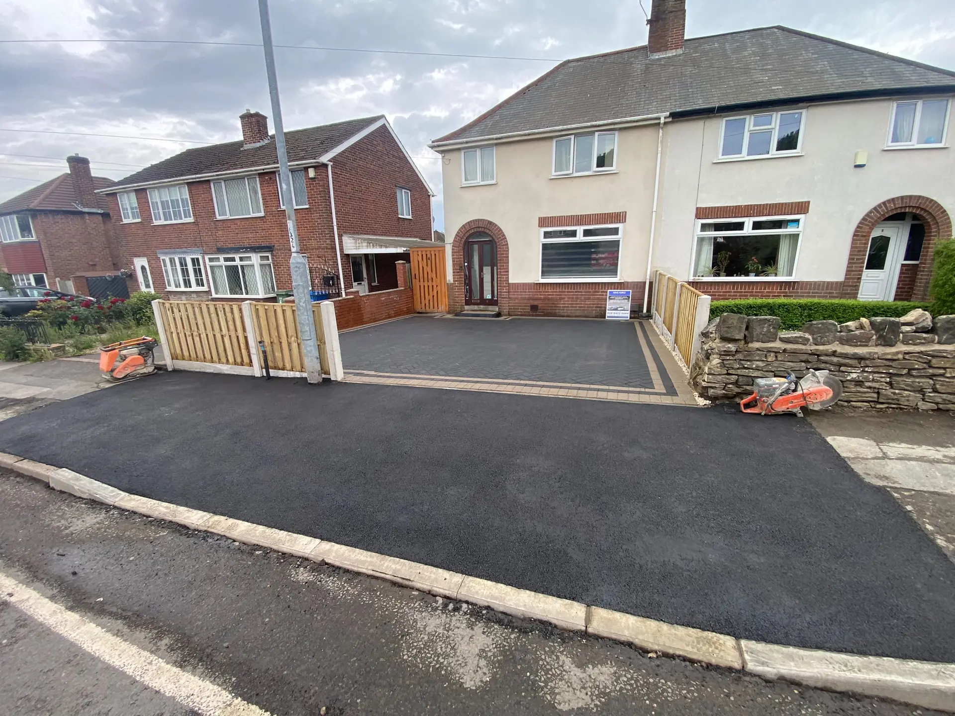 New tarmac crossing at the pavement edge with a block-paved driveway behind it
